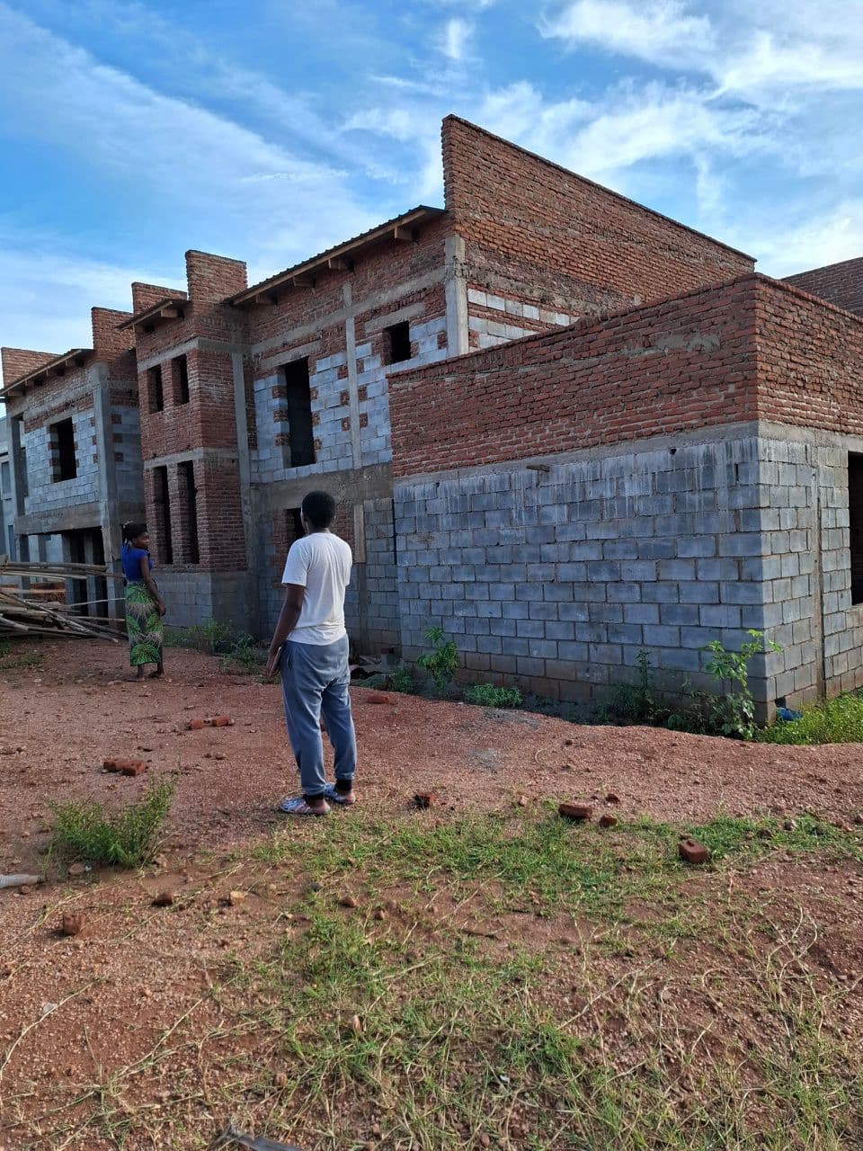 Roof timber structure and covering. Timber roof trusses/rafters were installed and roofing sheets fixed over a section of the building, while brickwork and gable walls were completed on the remaining portions. The building is progressing toward full roof cover ahead of finishing works.